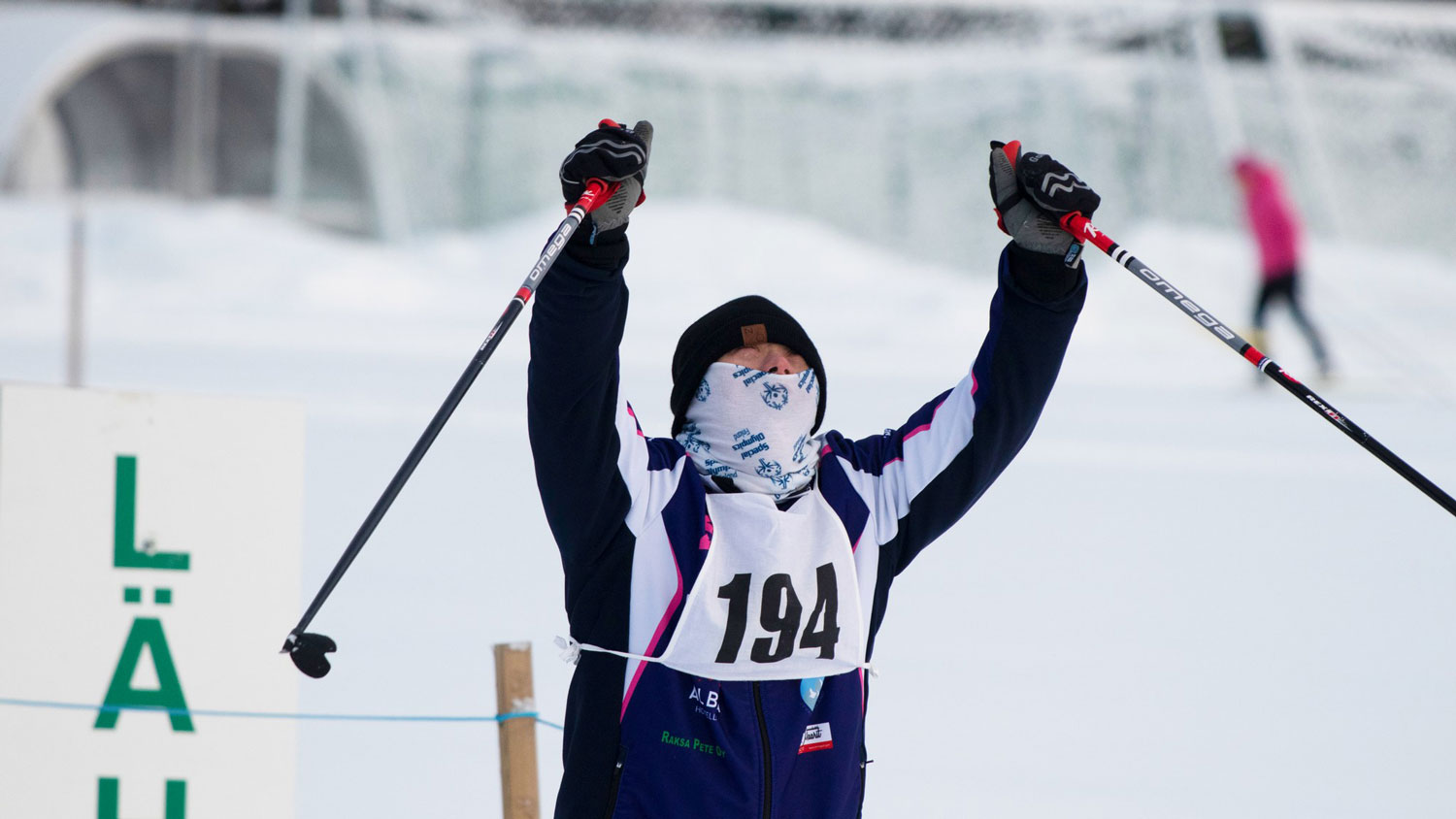 Special Olympics hiihtäjä tuulettamassa sauvat sivuilla iloisena.